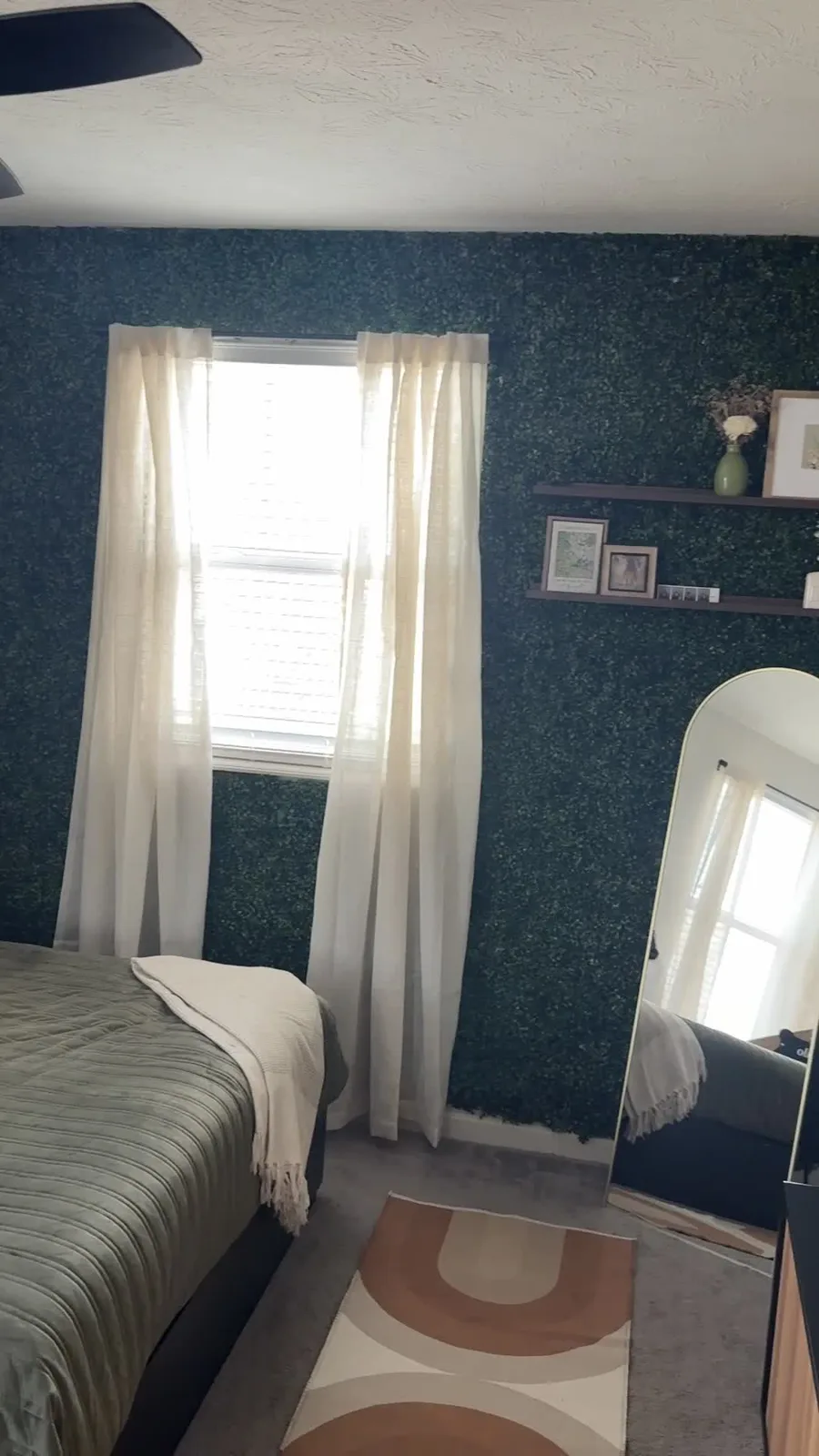 Kennedy's completed bedroom showing the dark botanical accent wall and bed styling