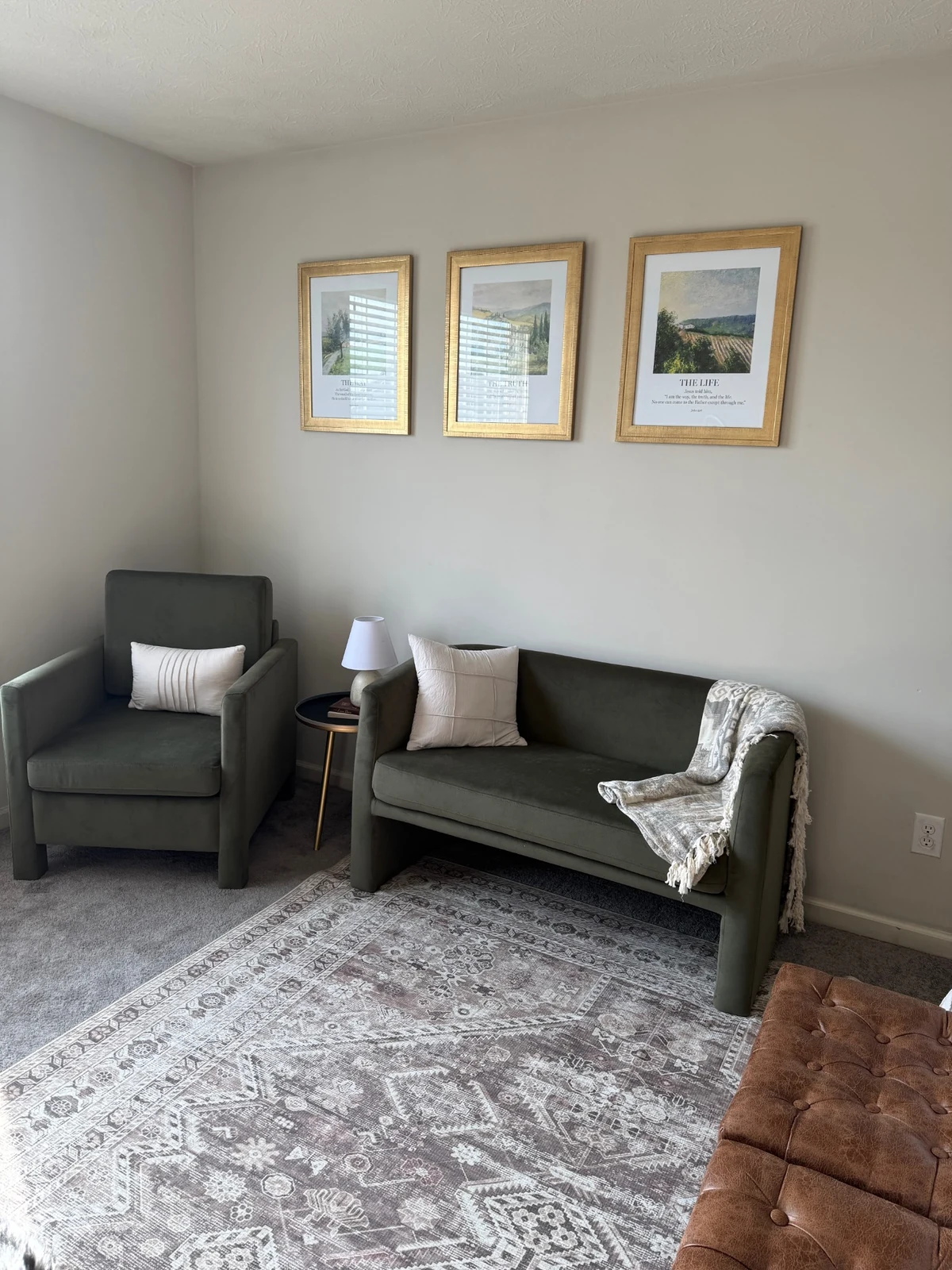Finished guest room sitting area with olive chair and loveseat, side table and framed art