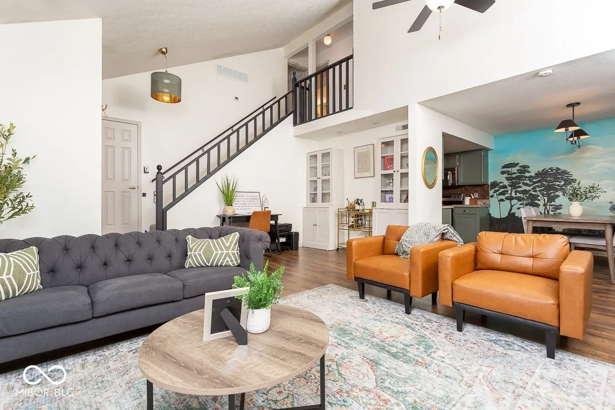 Zahria's condo completed living room with charcoal sofa, cognac chairs and rounded wood table